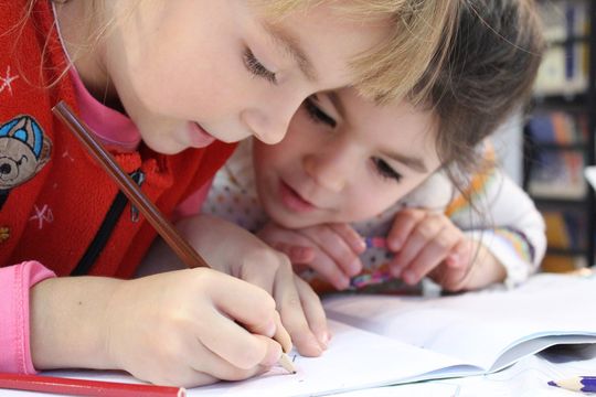 To skolebarn ser ivrig ned i skrivebok